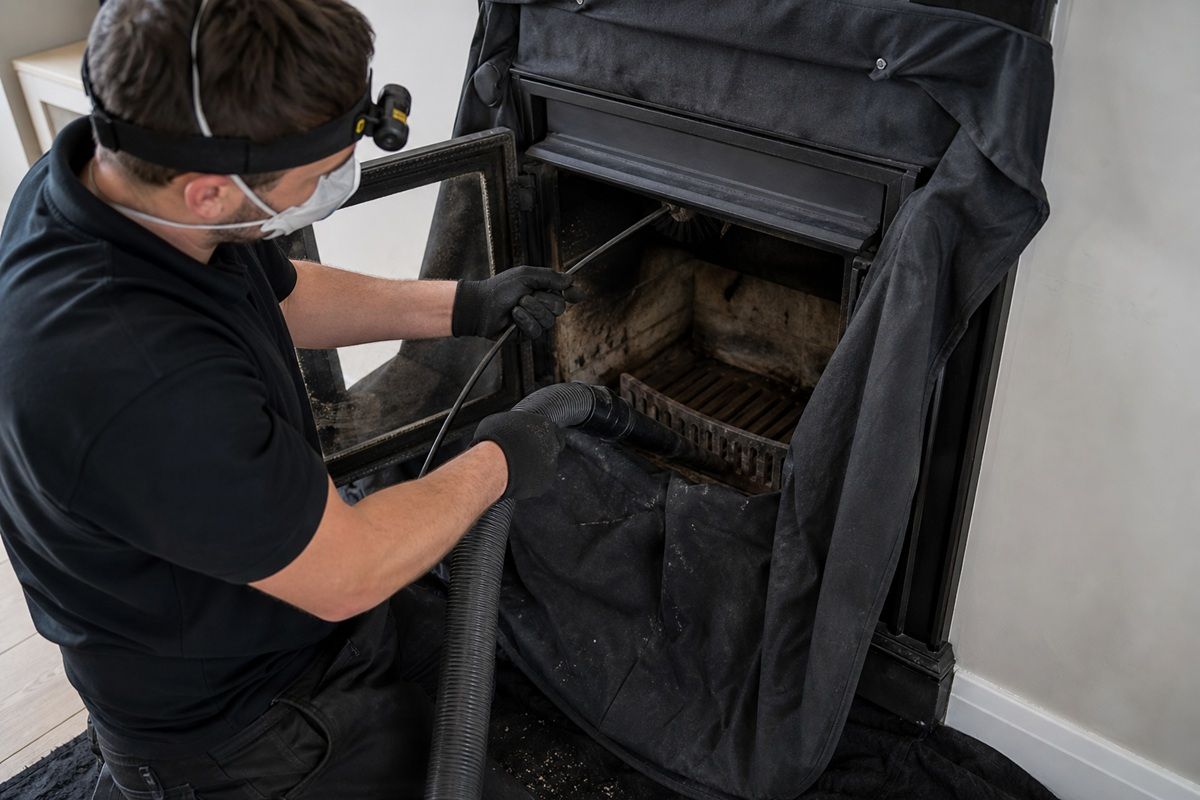 Careful indoor chimney cleaning with protective coverings around the fireplace
